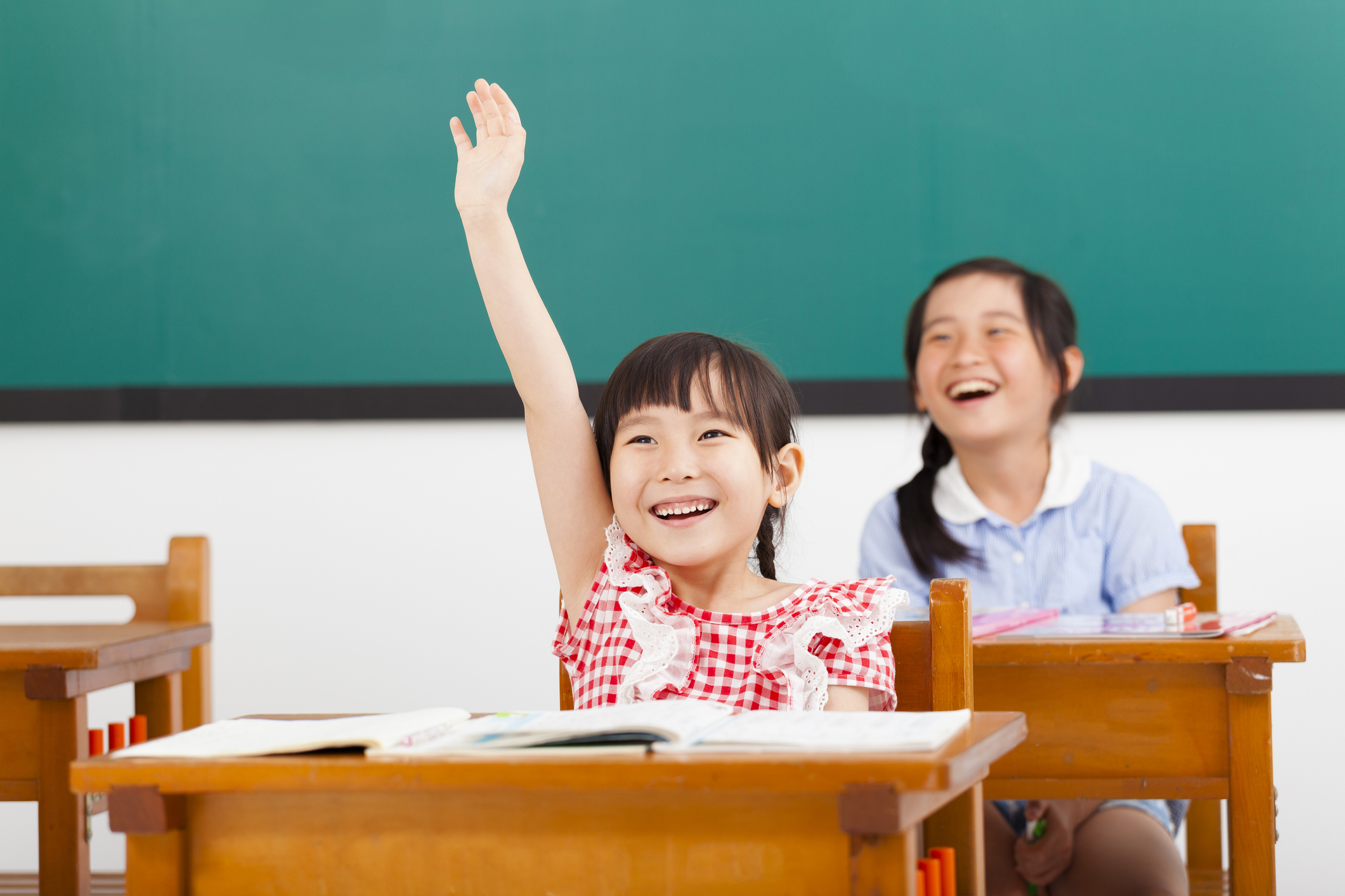 happy school children raised hands in class