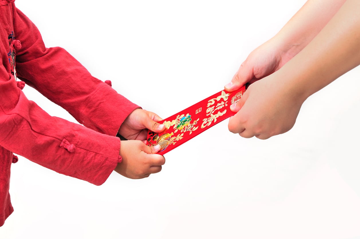 Asian child is holding red packets and Chinese calligraphy word of 'Ji xiang ru yi' meaning have one's wish fulfilled, isolated on white background, Chinese new year concept